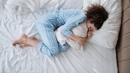 Top View Of Depressed Woman In Pajamas Lying In Bed In Bedroom.