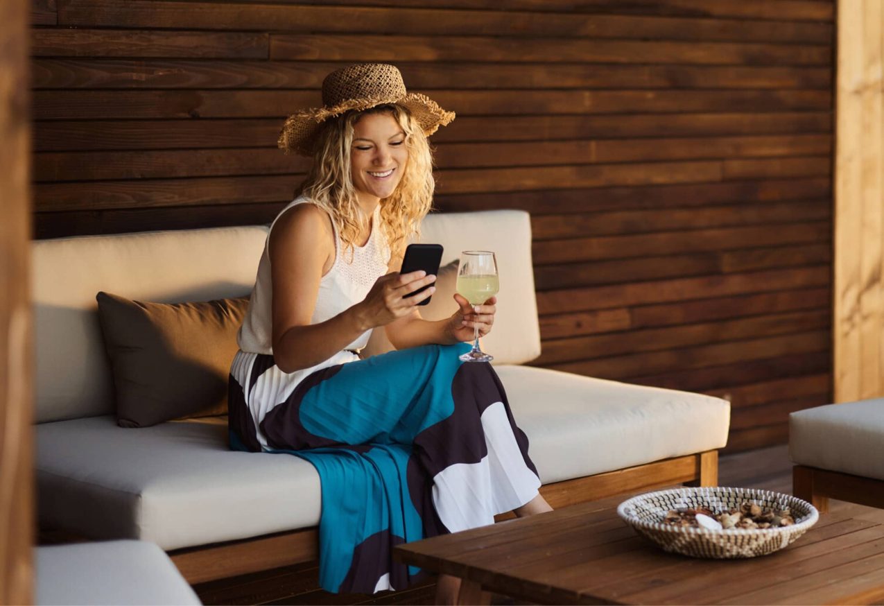 Loungesets Afgeprijsd: vrouw zit op loungeset en kijkt op haar telefoon