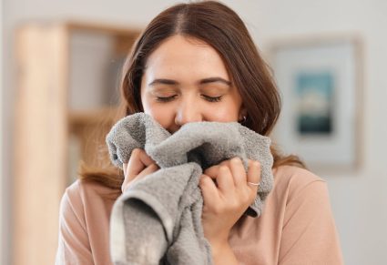 Wasparfum: vrouw ruikt gelukzalig aan wasgoed