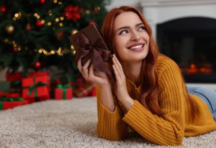 Rituals: vrouw ligt bij kerstboom met een cadeautje in haar hand