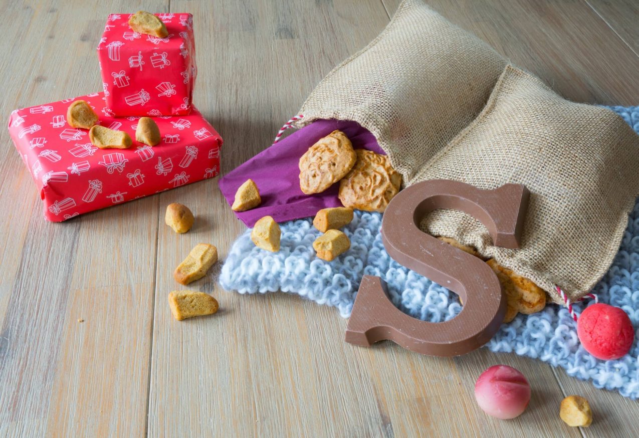 Schoencadeautjes Kleuters Peuters: Houten tafel met Nederlandse Sinterklaas snacks in jute zak, met gebreide servet, taai taai, geschenken