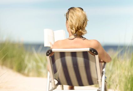 Meeslepende Thrillers: vrouw leest boek in strandstoel: op het strand