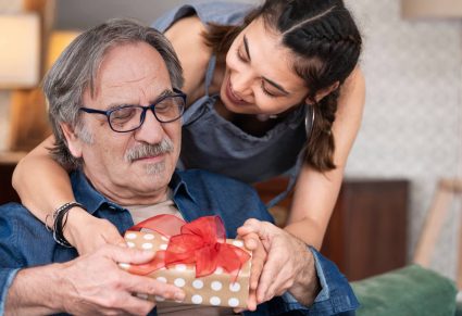 dochter geeft haar vader een populair vaderdagcadeau, ingepakt in pakpapier met een rode strik