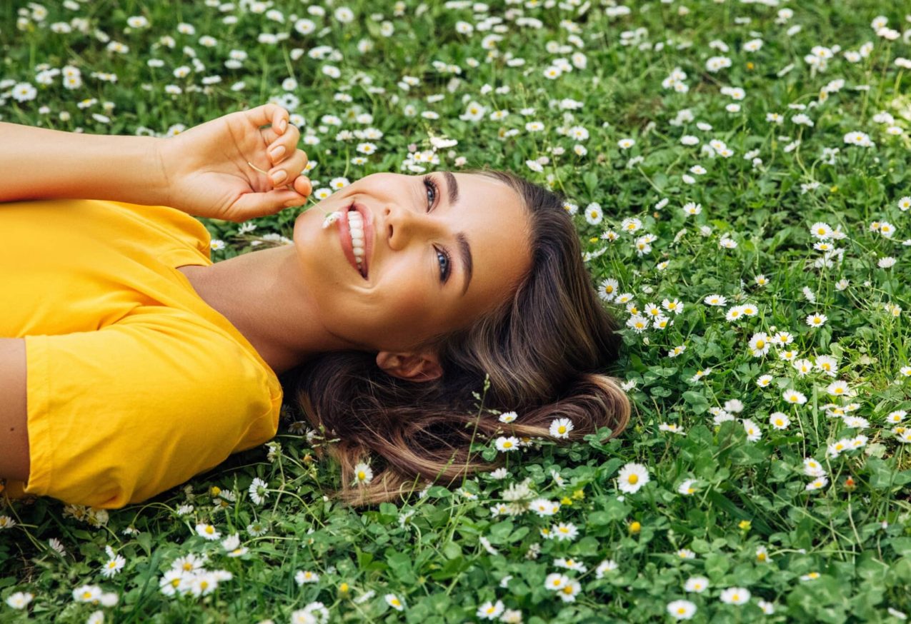 T-Shirtjurken: vrouw ligt in het gras met gele t-shirtjurk aan