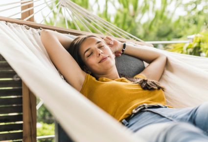 vrouw ligt in hangmat in haar onderhoudsvrije tuin