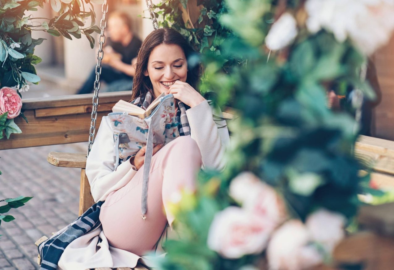 vrouw zit in gezellige tuin, ze leest een boek