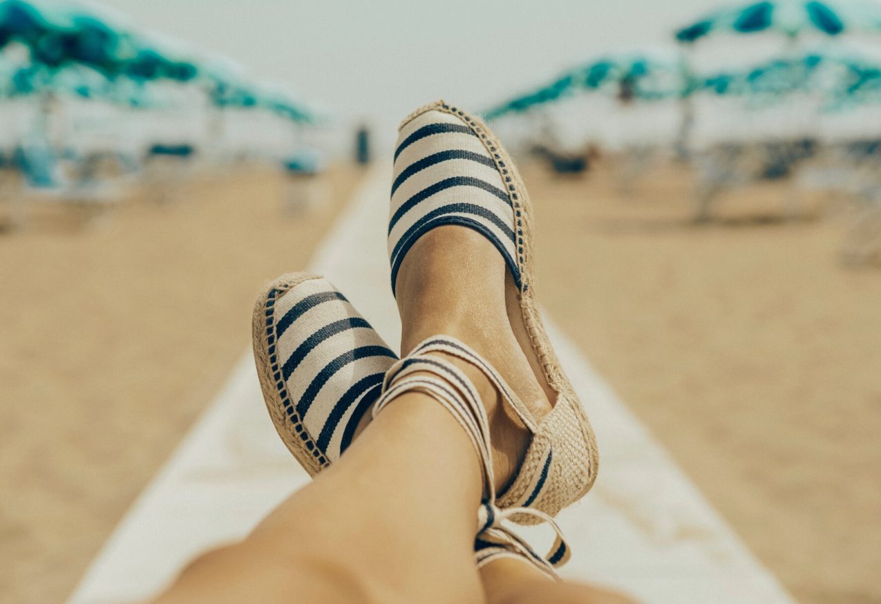 Espadrilles met op de achtergrond het strand met parasols