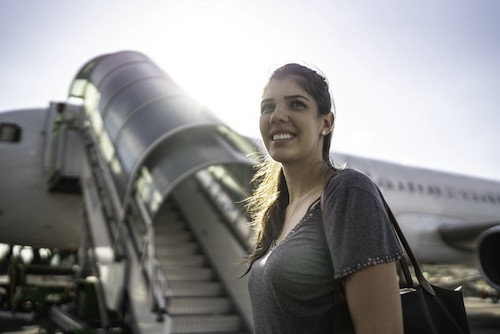 oorpijn in het vliegtuig: Vrouw voor een vliegtuig na de landing