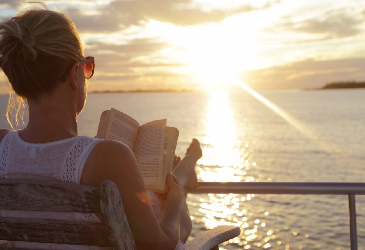 Topboeken Van Nederlandse Schrijvers: vrouw leest boek aan het water