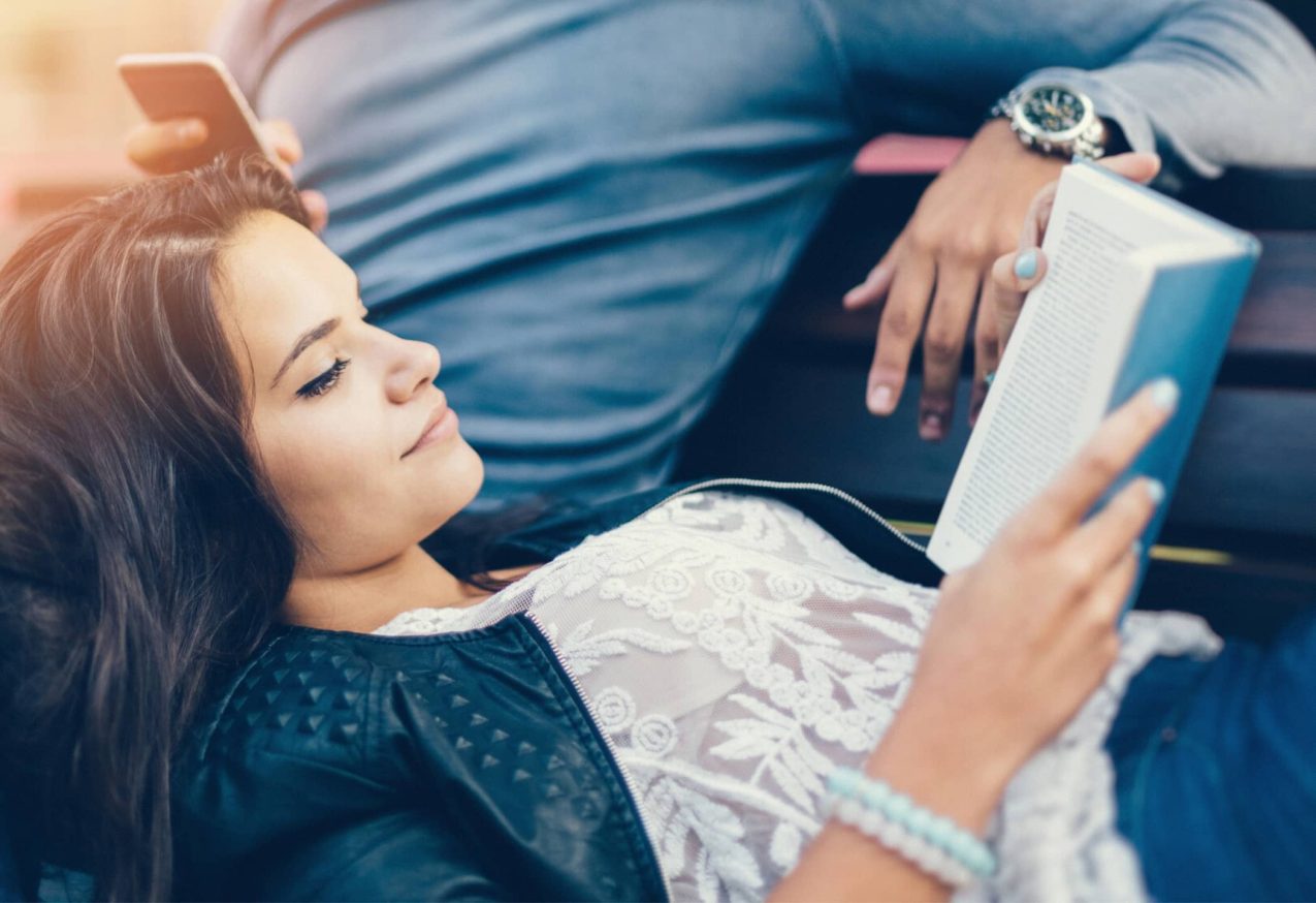 Zomerse romans: Vrouw Leest Boek en leunt tegen liefdespartner aan