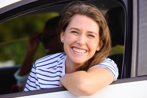 een jonge vrouw die uit een autoraam kijkt tijdens een autorit met haar man, frisse lucht tegen wagenziekte