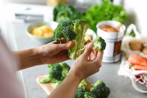 Vrouw snijdt broccoli in kleine stukjes voor de broccoli soep