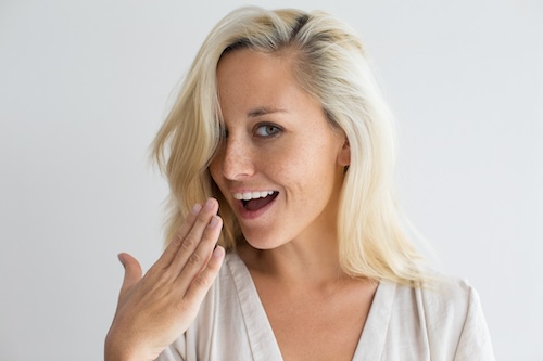 vrouw houdt haar hand voor haar mond en controleert haar frisse adem