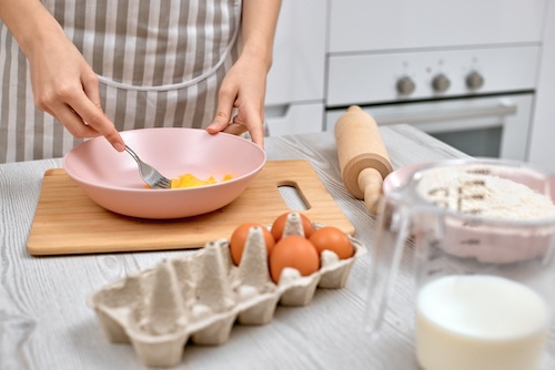 wentelteefjes recept: Vrouw slaat eieren in een kom. 