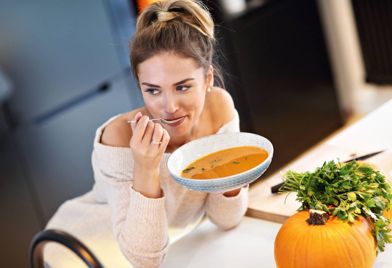 Herfstsoepen: vrouw eet pompoensoep