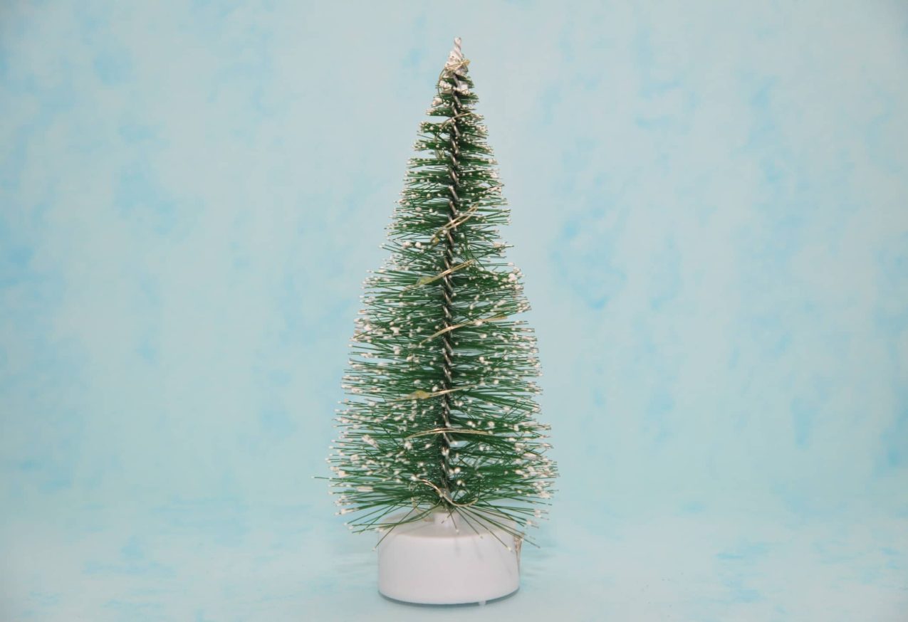 Kerstmusthaves: waxinelichtje met kerstboompje, blauwe achtergrond