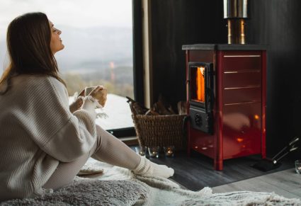 Raamdecoraties: vrouw zit met een kop thee bij de kachel en het raam