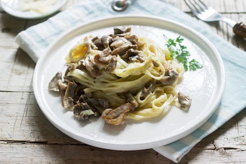 Tagliatelle With Cream And Forest Mushrooms Sauce In A White Plate On A Wooden Background. Rustic Style.