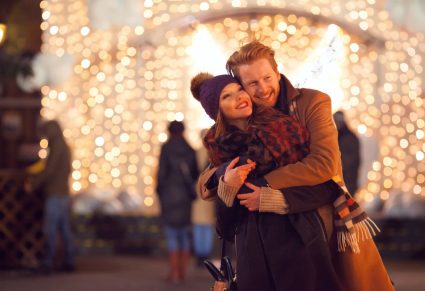 Europese Steden Kerstsfeer: stelletje in omhelzing met kerstlichtjes erachter