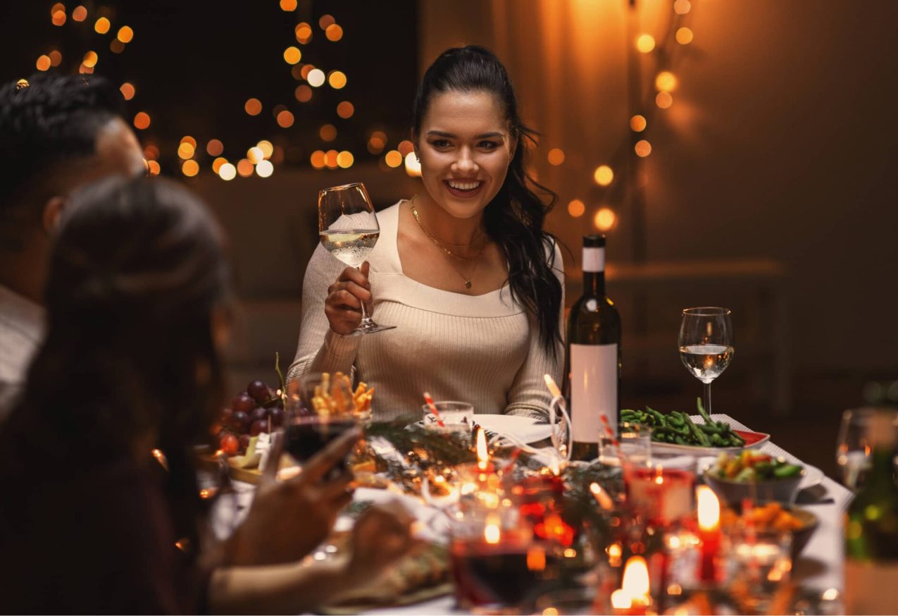 Feestelijke Jumpsuits: kerstdiner met vrouw die een glas wijn in haar hand heeft