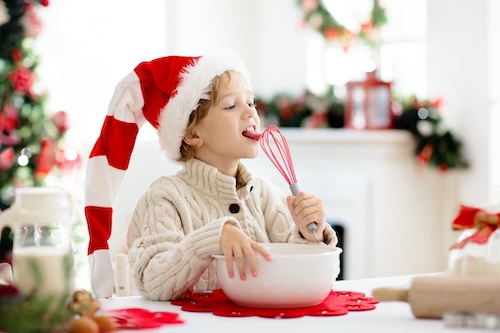 kerstrecepten: Jongetje met kerstmuts maakt deeg voor winterkoekje. 