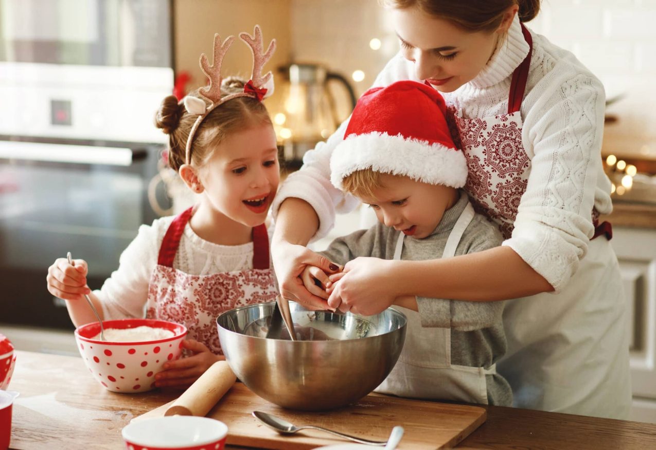 Kindvriendelijke Kerstrecepten: vrolijke moeder en kinderen bakken kerstkoekjes