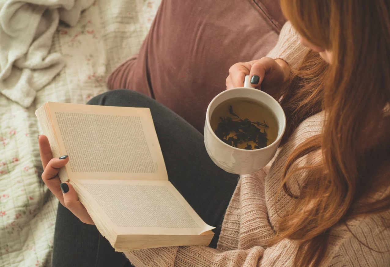 Onvergetelijke Thrillers: vrouw leest boek met kop koffie in haar hand