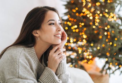 Schitterende Oorbellen: mooie vrouw zit bij kerstboom