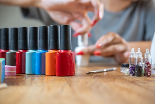 afbladderende nagellak voorkomen: Gekleurde nagellak met een achtergrond van een vrouw die haar nagels lakt.