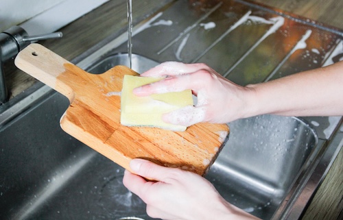 hoe schoon is jouw snijplank: persoon maakt snijplank schoon