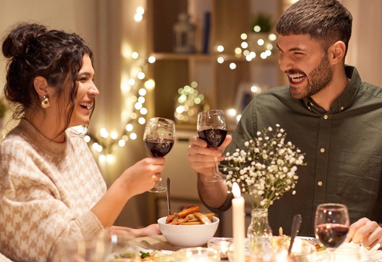 Hoofdgerechten Met Kerst: man en vrouw proosten aan de kersttafel