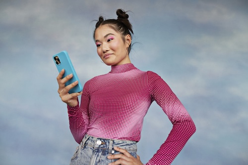 meisje bekijkt foto's op telefoon, blauwe achtergrond | perfect op de foto