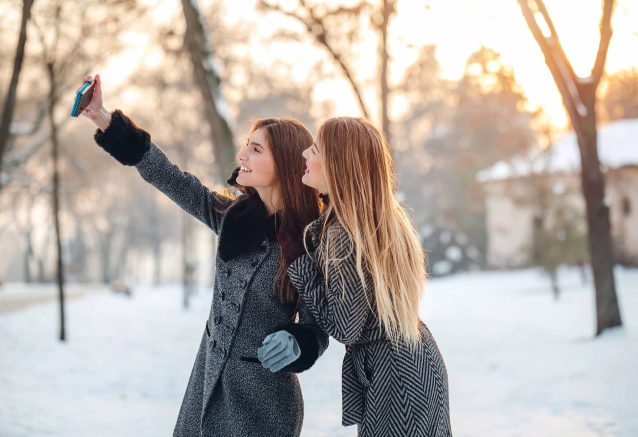 Selfie Maken: Twee jonge vriendinnen maken selfies in besneeuwd park