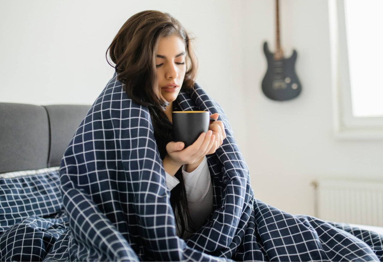 Vrouw In Bed Met Warmtedeken En Kop Thee