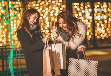 Wikkelvest Met Glitters: 2 vrouwen genieten van een avondje winkelen en lachen terwijl ze in elkaars tassen kijken